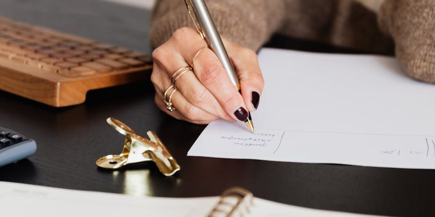 crop elegant business lady taking notes while sitting at desk