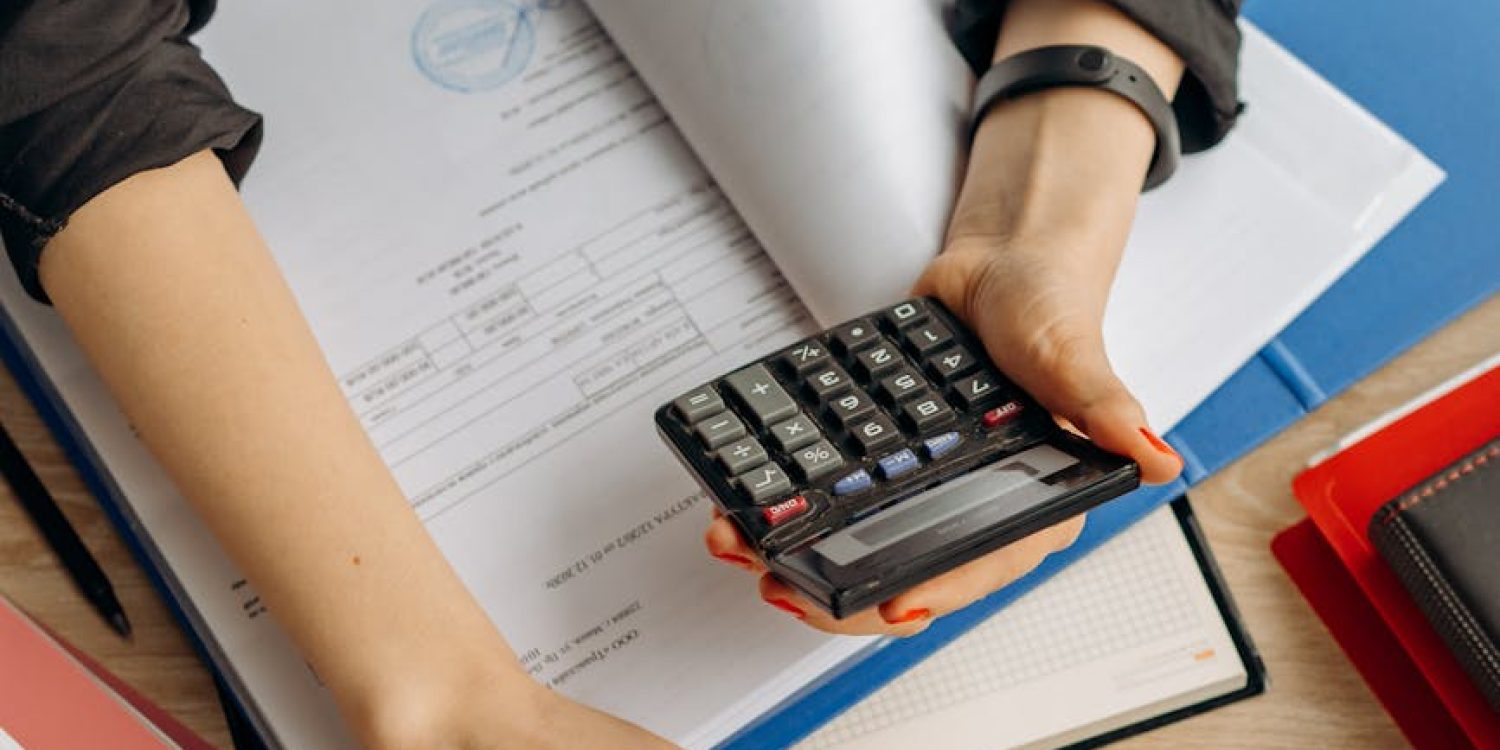 person holding black calculator while using laptop